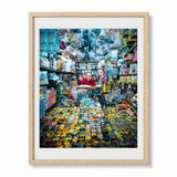 A framed art print featuring a colorful photograph of Akihabara man in Japan in his electronics store, displayed in a light natural wood frame with a white mat against a plain white background.