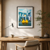 A framed wall art print hangs above a wooden desk in a styled home office. The print shows a Hong Kong skyline with two bright yellow rubber ducks floating on water.