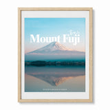 Framed wall art featuring mount fuji reflected over water and decorative text showing the word "Mount Fuji" and the coordinates presented in a wood frame.