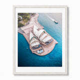 A framed aerial photograph of the Sydney Opera House surrounded by bright blue water, presented in a light-colored wooden frame against a white background.