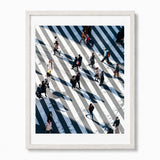 A framed art print featuring an aerial photograph of people crossing Shibuya Crossing in Japan, presented in a light-colored wooden frame against a white background.