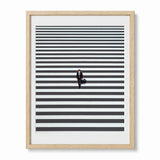 Framed minimalist wall art featuring a small figure in a suit walking across a pedestrian crossing in Shinjuku Japan, shown in a light wood frame.