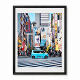 A framed art print depicting a vibrant street scene in Tokyo, Japan, featuring a light blue car on a crosswalk surrounded by tall buildings and colorful neon signs, presented in a black frame with a white mat.