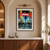 Framed wall art featuring people walking in Shinjuku Tokyo at night and neon signs in the background, shown in a black frame hanging on a wall in a home.