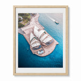 Framed aerial photograph of the Sydney Opera House surrounded by bright blue water, shown in a light wood frame against a white background.