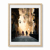 A moody photograph print of a barcelona street, framed in a light wood frame. 