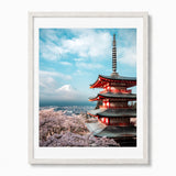 A framed art print featuring a Japanese pagoda, cherry blossoms, and Mount Fuji under a blue sky, presented in a white frame against a light gray background.