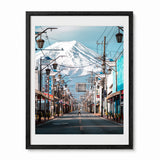 A framed photographic art print of a Japanese street scene with mount Fuji in the background, shown against a plain white wall.