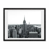 A framed landscape black and white photography print of the empire state building and new york city scape, set in a black frame