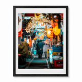 A framed photographic art print of a Japanese street scene at night, featuring warm orange lanterns, a person walking away in Tokyo's memory lane, presented in a black frame with a white mat against a white background.