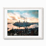 A framed panoramic photograph of the Shanghai skyline at sunset, featuring the Huangpu River, modern skyscrapers, and the Oriental Pearl Tower, presented in a white frame against a light gray background.