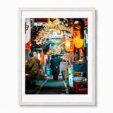 A framed photographic art print of a Japanese street scene at night, featuring warm orange lanterns, a person walking away in Tokyo's memory lane, displayed in a white frame.
