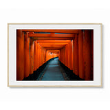 Framed landscape wall art featuring a tunnel of red orange torii gates in Kyoto, Japan - shown in a wood frame with white mat on a light gray background.