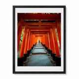 A framed art print depicting a perspective view down a stone path lined with vibrant orange torii gates, enclosed in a black frame with a white mat border.