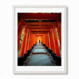 Framed wall art featuring a photograph of a pathway lined with bright orange-red torii gates, shown in a white frame against a light gray background.