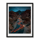 A framed vertical art print depicting a winding road through the Valley of Fire State Park in Nevada. The print is  enclosed in a black frame.